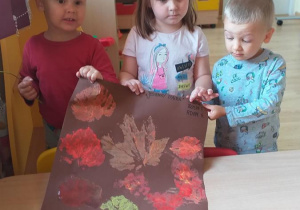 Adaś, Zosia i Miłosz prezentują wykonany przez siebie "jesienny dywan".